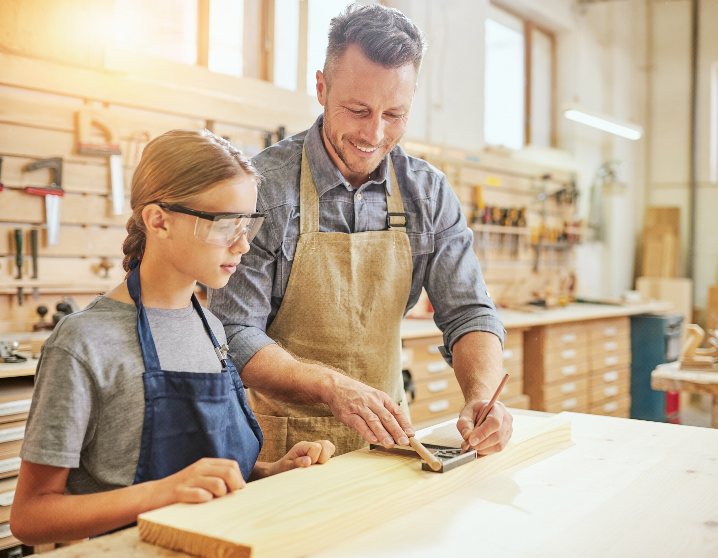 Adult mentor showing a young maker a woodworking task at the bench